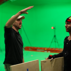 Man in front of green screen with actor in mo cap suit