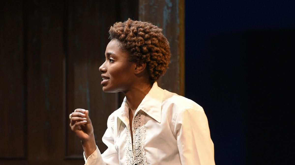 woman onstage delivering lines in white blouse