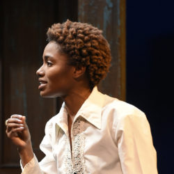 woman onstage delivering lines in white blouse