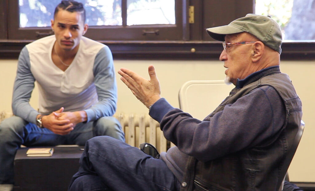 Professor Andrei Belgrader talking and gesturing class with an MFA Acting student listening