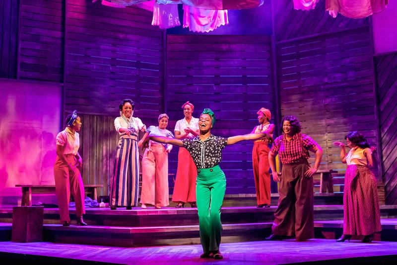 A group of actors onstage in colorful costumes.