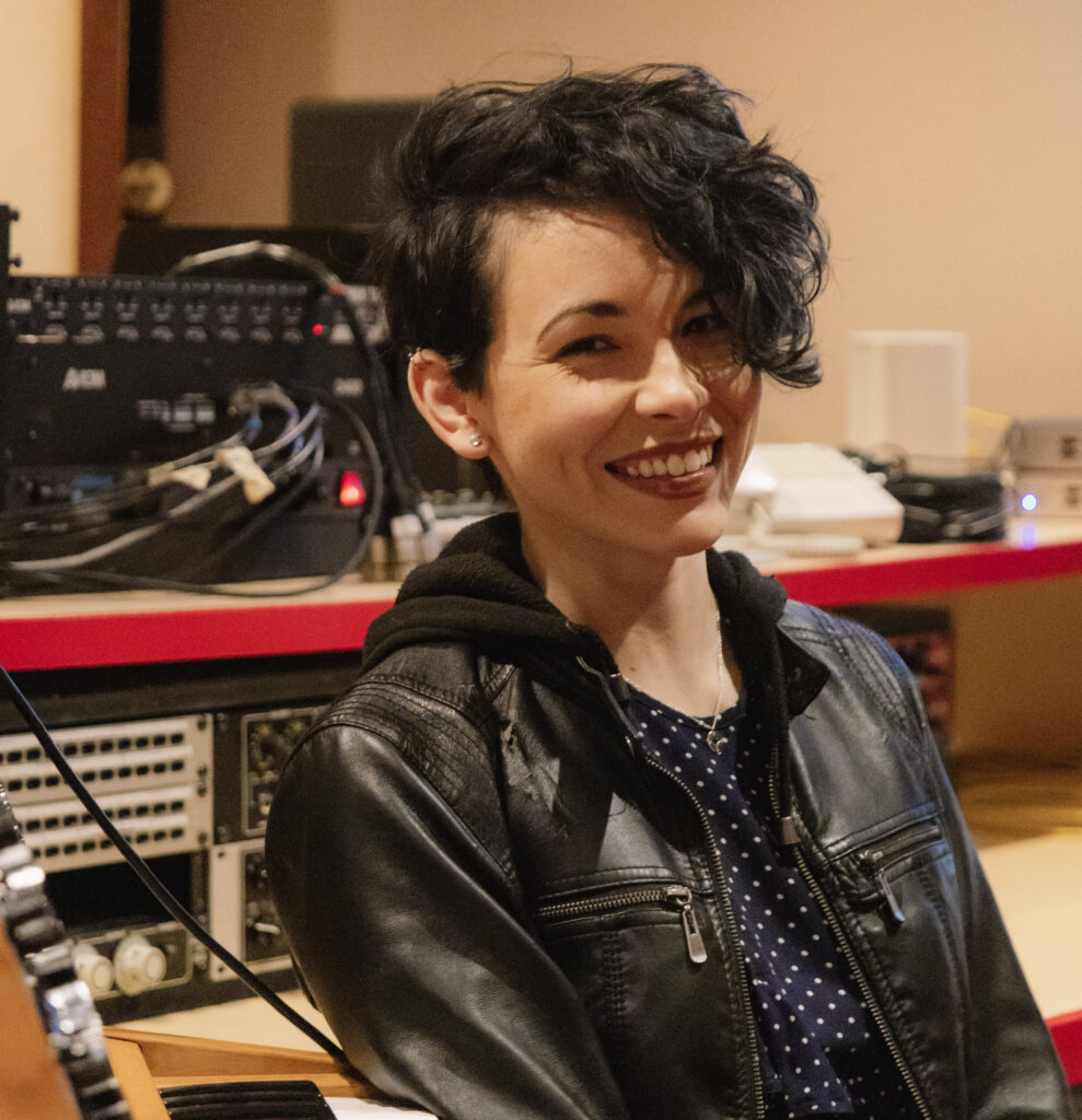 Assistant Professor of Sound Design Noel Nichols sitting next to a console