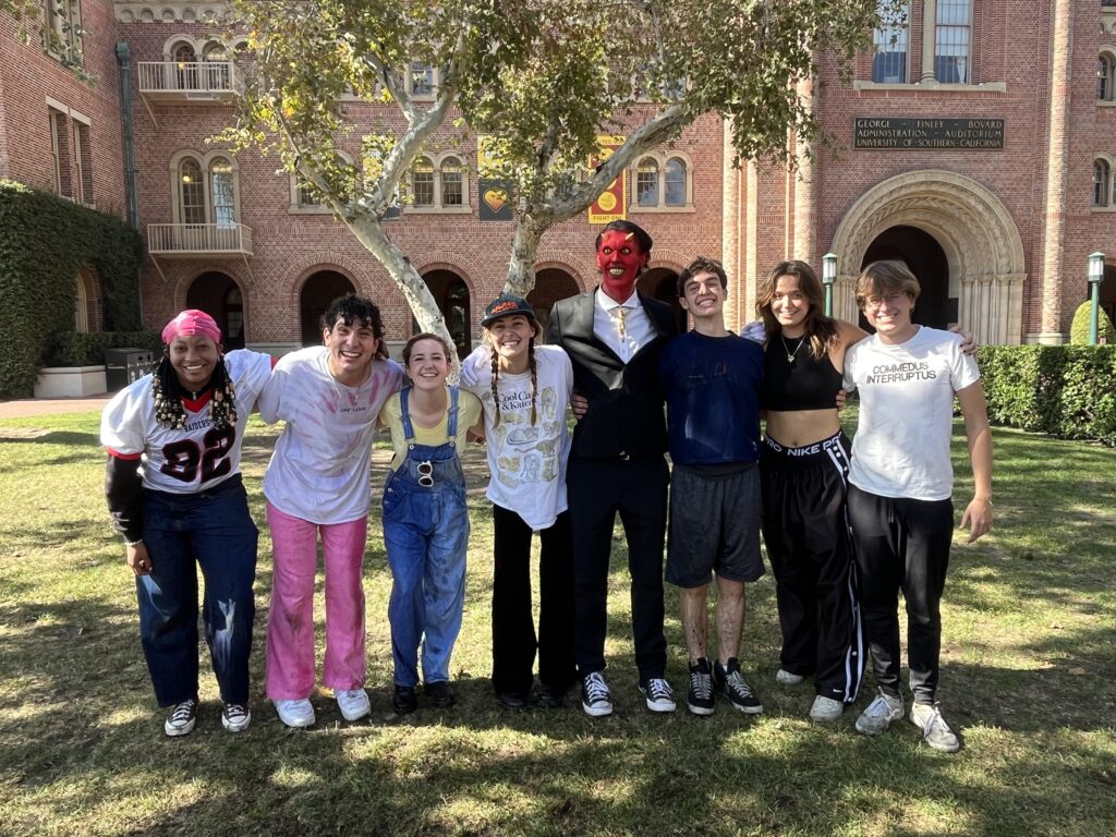 Eight students with arms around shoulders on a lawn