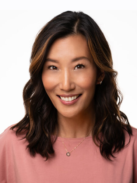 a photo of faculty member Esther K. Chae smiling at the camera wearing a pink shirt