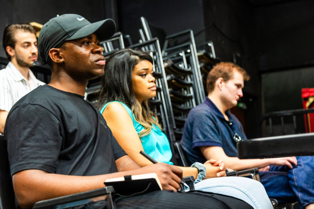 Three audience members sit side by side looking thoughtful and watching the panel.