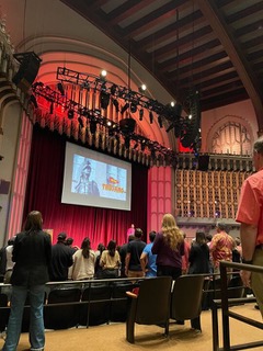 Auditorium full of students watching an orientation presentation.