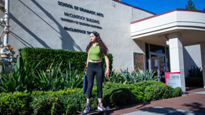 A student rides their skateboard past the McClintock Building.