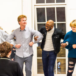 Jonathan Mangum, Wayne Brady and two students lock arms in an improv comedy sketch.