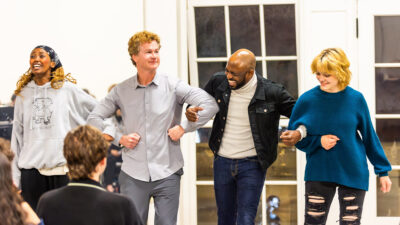 Jonathan Mangum, Wayne Brady and two students lock arms in an improv comedy sketch.