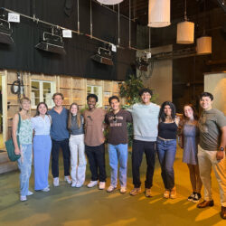 Ten SDA students stand side by side in front of the set of a house.