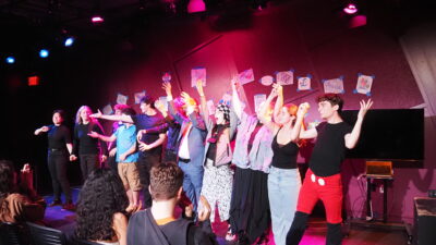 Members of Ludus Remedium onstage with arms clasped in a curtain call.