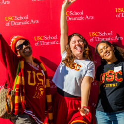 Three Trojans in cardinal and gold joyously signal 