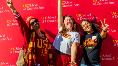 Three Trojans in cardinal and gold joyously signal 