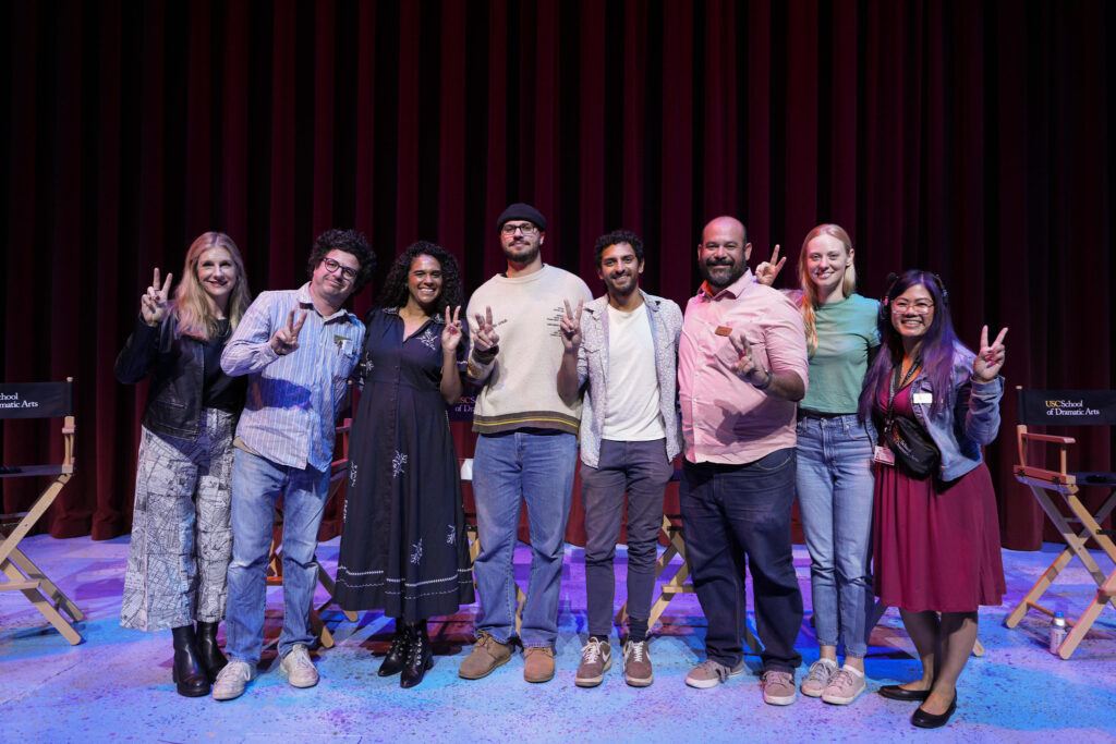 The panelists and moderator flash "fight on" signs with Dean Emily Roxworthy and Events Manager Jennifer Franco.