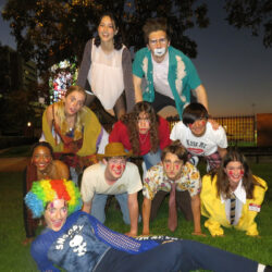 Members of Second Nature Improv form a human pyramid on the grass.