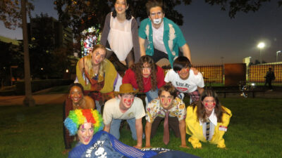 Members of Second Nature Improv form a human pyramid on the grass.