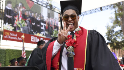 A happy graduate signals 'fight on' to the camera.