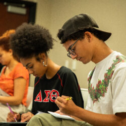Several USC School of Dramatic Arts students sit around a table writing letters during the launch of The Aerin Project.