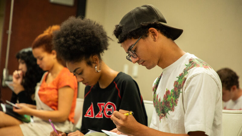 Several USC School of Dramatic Arts students sit around a table writing letters during the launch of The Aerin Project.
